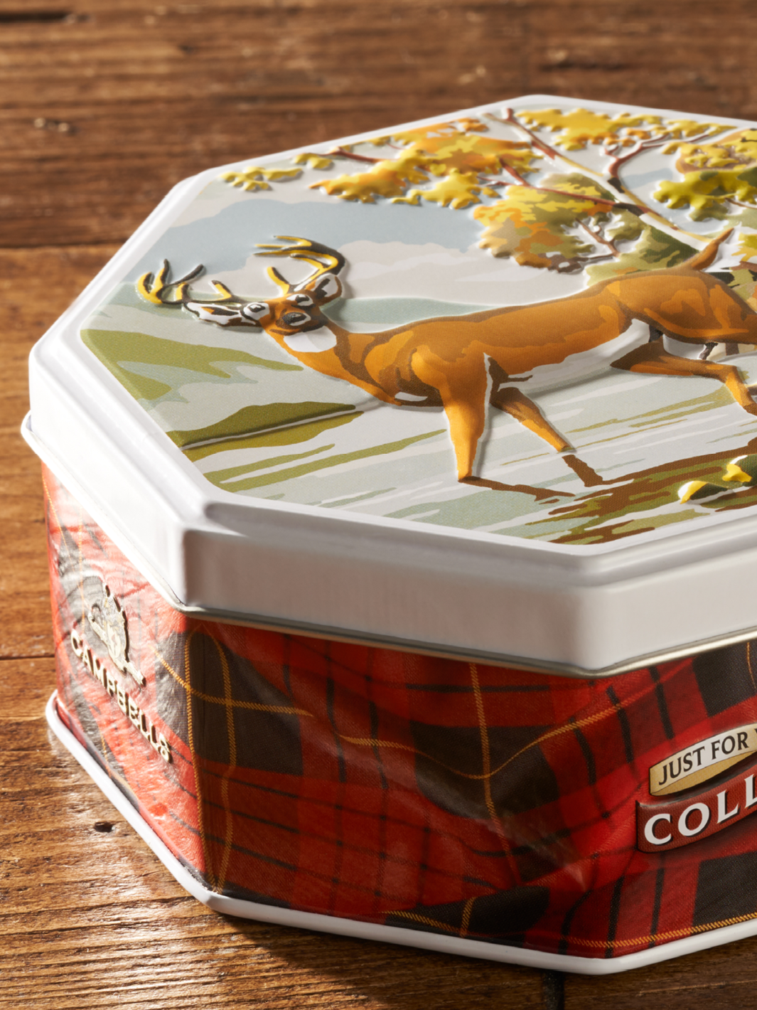 Una lata de metal personalizada con un grabado 3D en la tapa de un ciervo en un bosque. 
