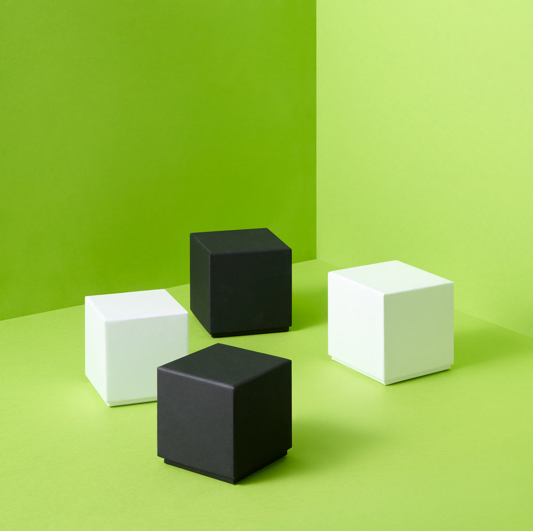 Cajas de regalo rígidas blancas y negras sobre fondo verde 
